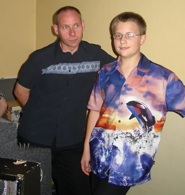 Colin and a young Darren posing together at a disco in October 2002, Darren in a bold dolphin print shirt