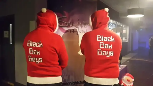 Two people seen from behind in red Santa hoodies printed with Black Box Boys