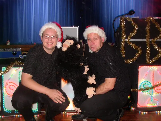 Darren and Colin in Santa hats with monkey puppets in front of the light-up BBB letters